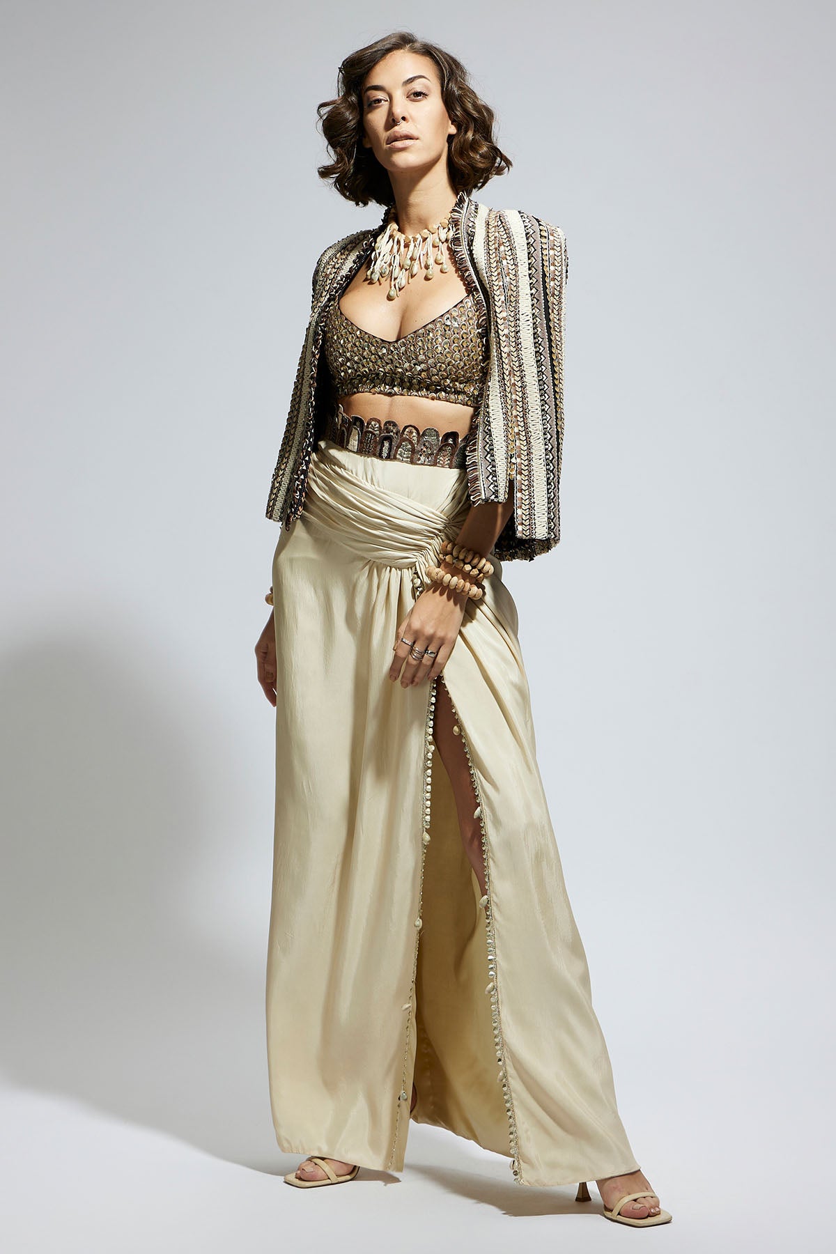 Embellished & Textured Cape Jacket Paired with Metallic Scallop Bustier and Ivory High Slit Skirt