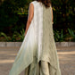 Box pleat pants and an embroidered vest are paired with a long cape